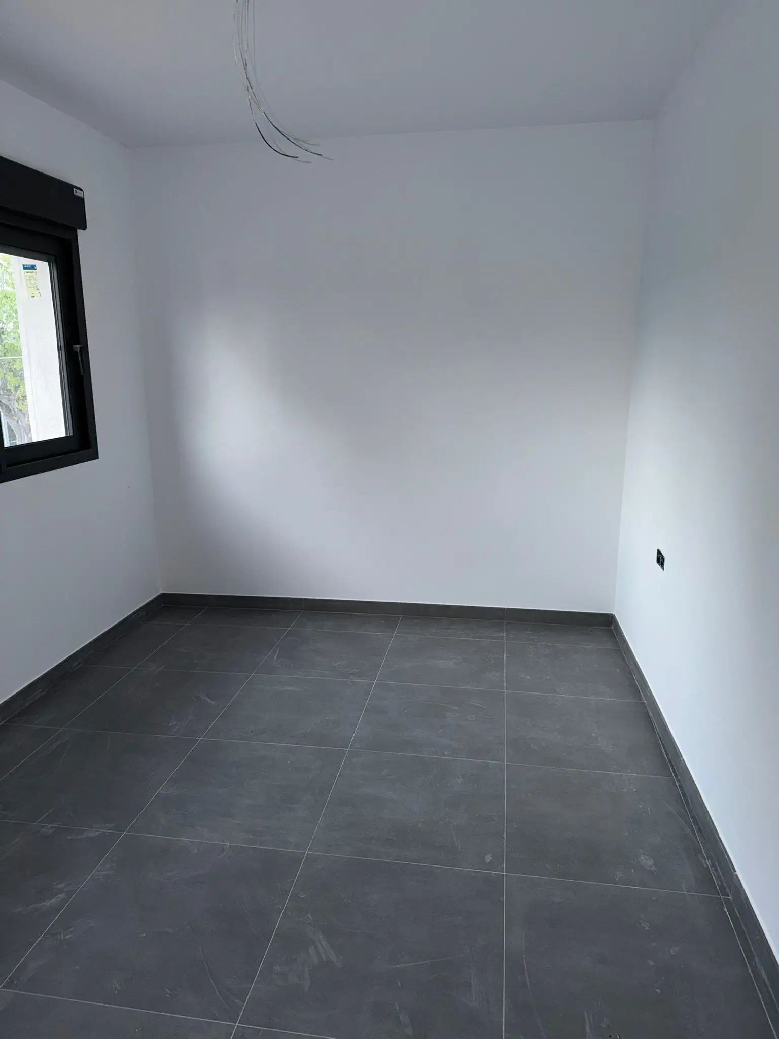 Reforma de vivienda con suelo de gres gris oscuro y paredes blancas recién pintadas en Valencia