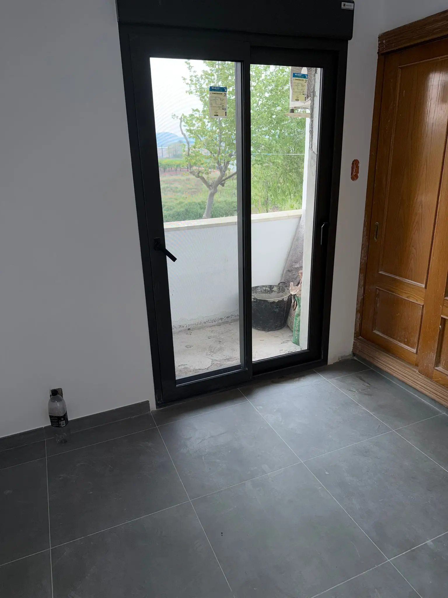Reforma de vivienda con suelo de gres gris y ventanal de aluminio negro en Valencia
