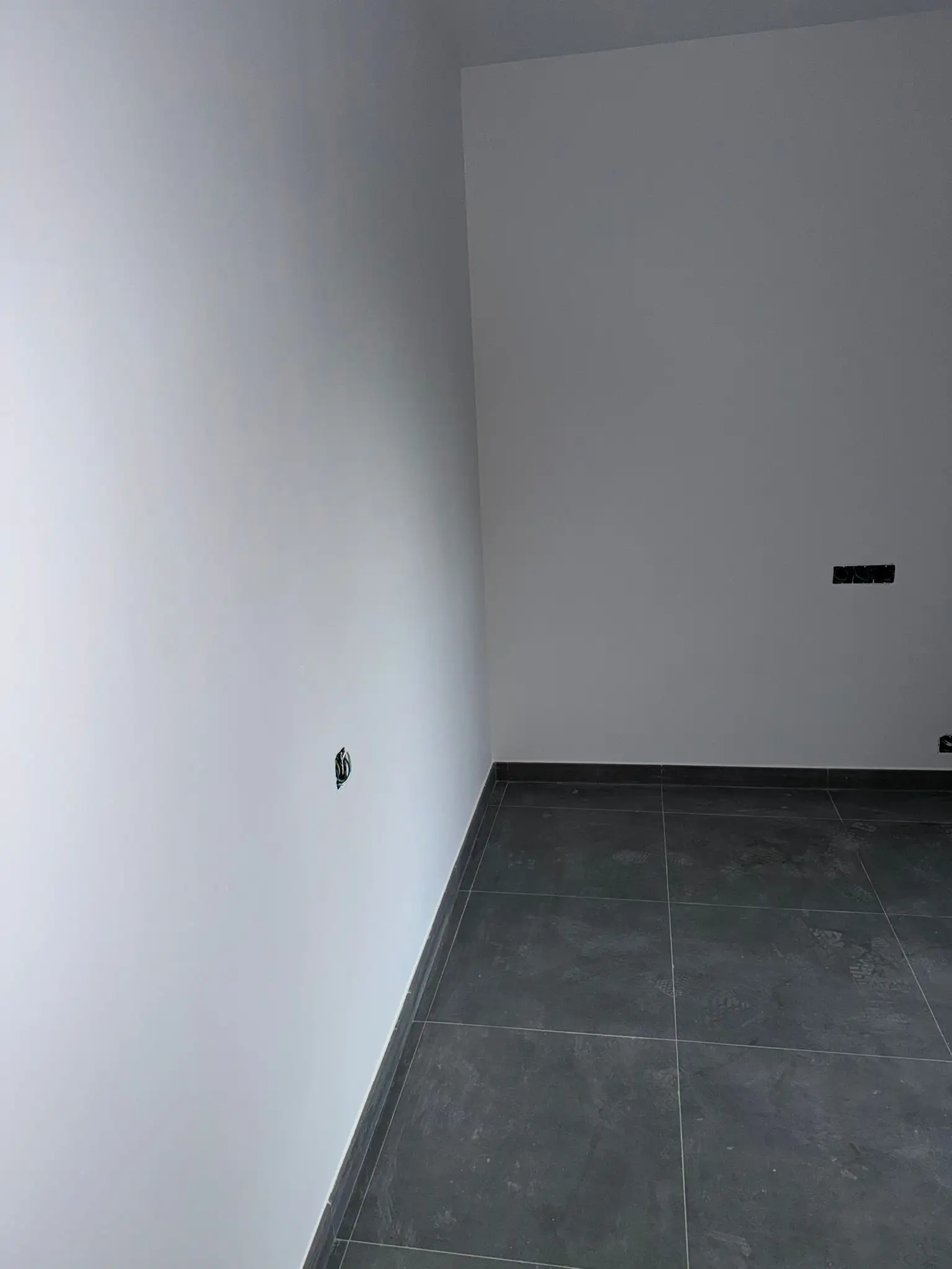Reforma de vivienda con suelo porcelánico gris oscuro y paredes blancas recién pintadas en Valencia