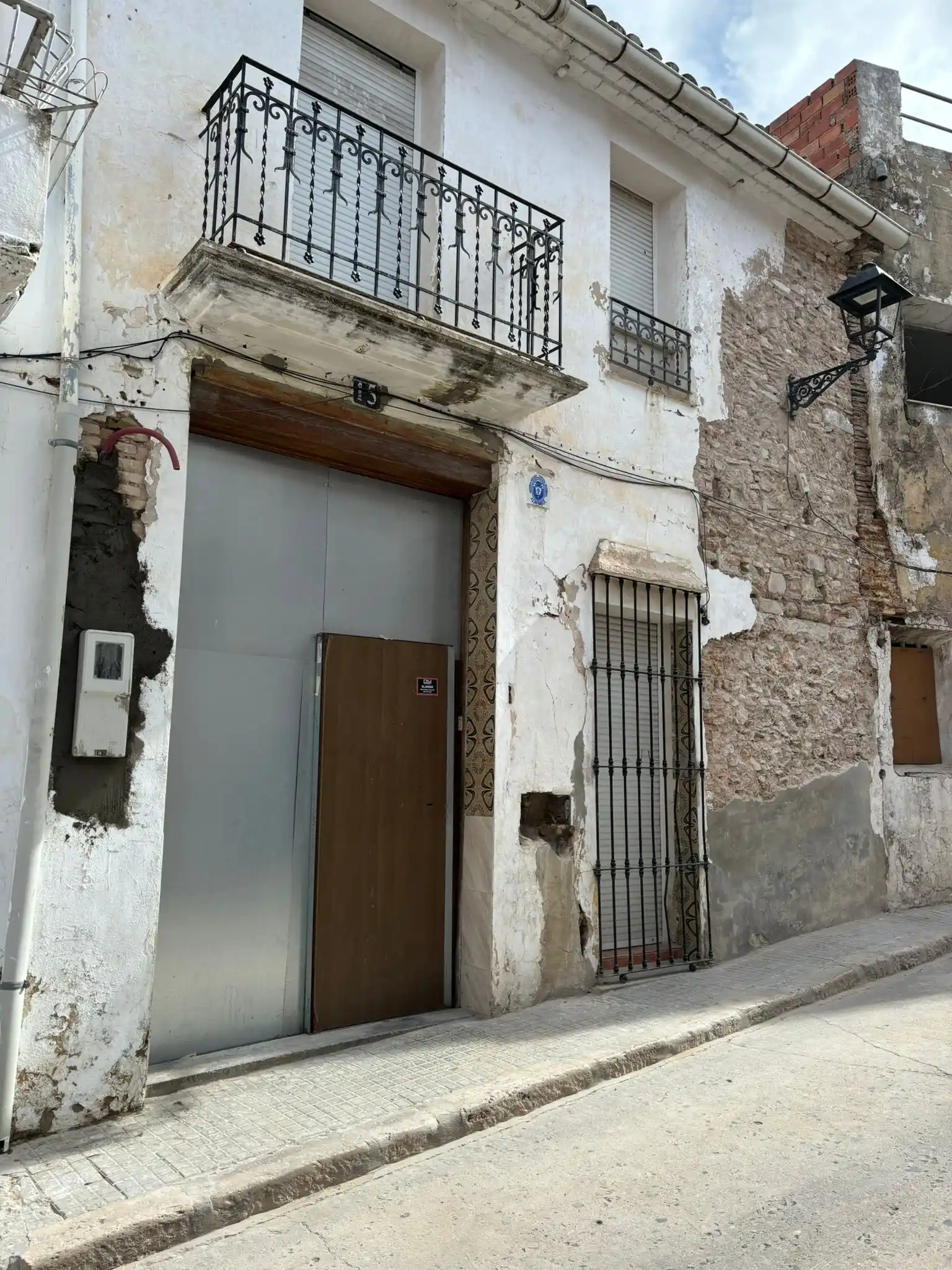 Rehabilitación de fachada antigua con muros de piedra vista y balcones de forja en Valencia